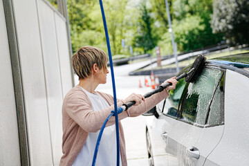 Focused and thorough, cleaning car windows with a water brush