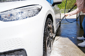 Water splashes off the car wheel as it's meticulously cleaned