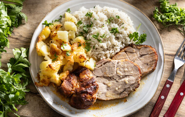 A portion of baked juicy neck on a plate with a side dish of potatoes and rice and a sauce with baked goods - 794920456