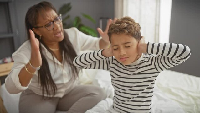 Mother scolding her young son in a bedroom, expressing family dynamics and parenthood at home.