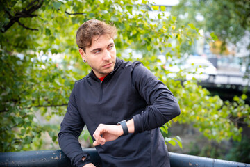 Sportsman looking at smartwatch with blank screen outdoors. - obrazy, fototapety, plakaty