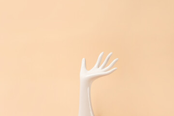 White ceramic statue hand on beige background with copy space