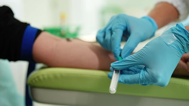 Closeup of unrecognizable female lab assistant wearing medical gloves taking venous blood from arm of woman patient for examination or PRP procedure. Concept of laboratory research, medicine, analysis