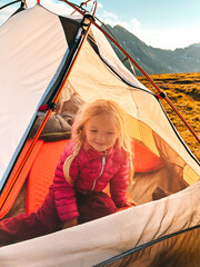 Child girl in camping tent on summer vacations active family lifestyle, travel in mountains with climbing gear kid hiking outdoor adventure tour