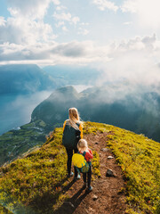 Family mother and child with backpack hiking in mountains together exploring Norway healthy...