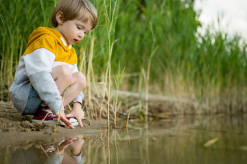 Cute little boy playing by a lake or river on hot summer day. Adorable child having fun outdoors during summer vacations. - 794971082
