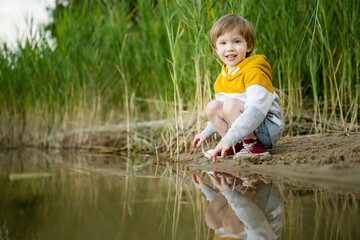 Cute little boy playing by a lake or river on hot summer day. Adorable child having fun outdoors during summer vacations. - 794971418