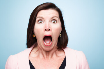 Portrait, wow and surprise of shocked woman with fear in studio isolated on a blue background....