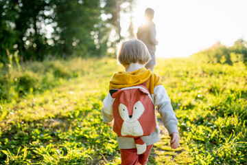 Cute little boy with a backpack having fun outdoors on sunny summer day. Child exploring nature. Kid going on a trip.