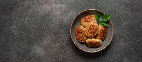 Fried meat cutlets in a bowl on a dark rustic background. Top view, copy space, banner.