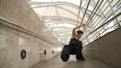 Motion shot of skilled handsome hipster perform street dancing at narrow corridor. Professional hip...