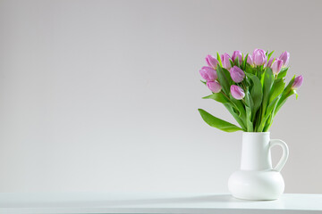 pink tulips in white jug on white background