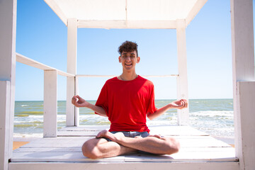 A young attractive man meditates by the sea.