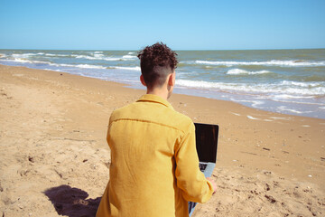 A young attractive man relaxes and studies by the sea.