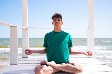 A young attractive man meditates by the sea.