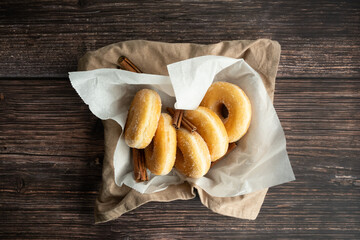 Sugar iced donuts with cinnamon wooden background. Overhead view. Desert Snack.