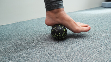 Massaging foot with a relaxing roll. Woman massaging foot with massage ball. Myofascial relaxation...