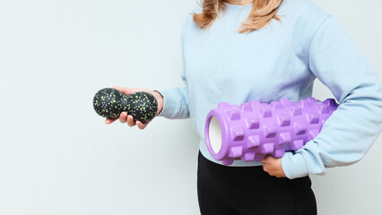 Woman holding massage rollers for myofascial release in her hands. Fitness trainer with items for...