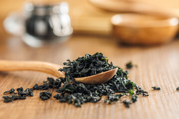 Dried wakame seaweed in spoon on wooden table. - 794992609