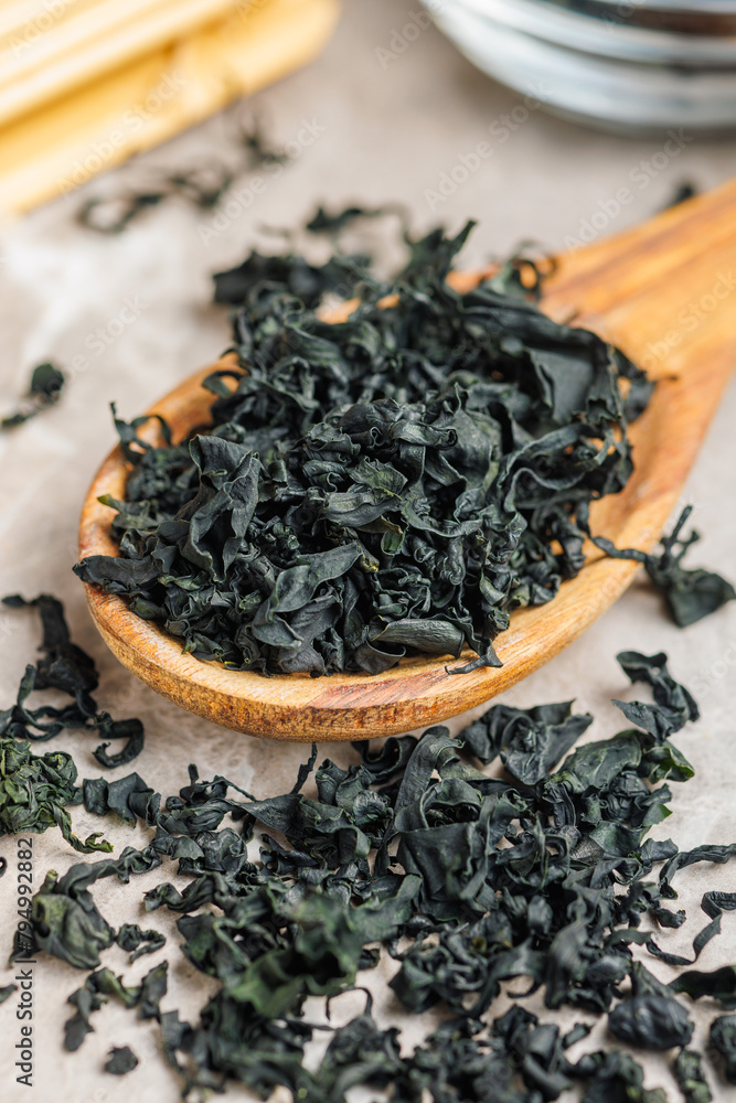 Sticker Dried wakame seaweed in spoon on kitchen table.