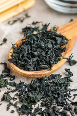 Dried wakame seaweed in spoon on kitchen table. - 794992882