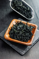 Dried wakame seaweed in bowl on black table.