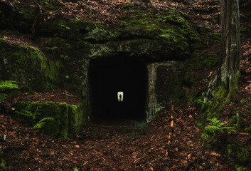 A person walks through a tunnel in rainy weather, old abandoned building