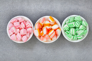 flat lay of old fashioned colorful sweets in bowls on mottled grey with copy space