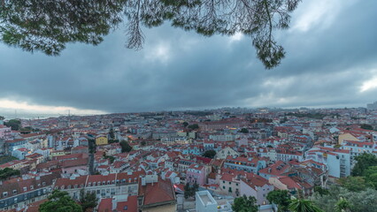 Panorama showing aerial cityscape day to night transition from Miradouro da Graca viewing point in...