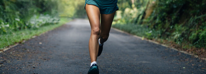 Sportswoman runner running on tropical park trail