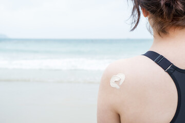 Smear of sunscreen in the shape of heart on female shoulder close-up against the background of the...