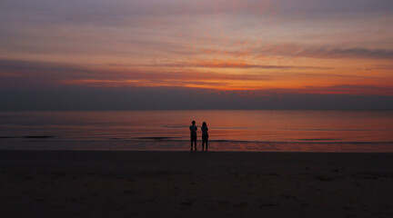 silhouette of The couple standing at the Beach looking Sunrise at the beach of Thailand