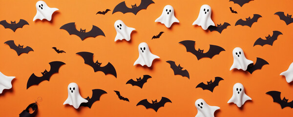 Fototapeta premium A collection of spooky Halloween decorations on a bright orange background. Bats and ghosts create a festive and spooky atmosphere. Halloween theme.