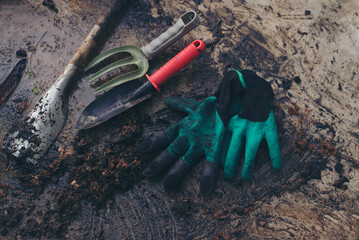 Gardening equipment (Dirty trowel, shovel, pruning, gardening fork, and glove) placed on soil and...