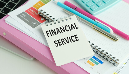 Financial Service text on a notebook with pen and laptop on business background