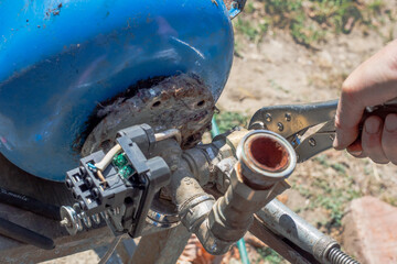 Water system. A man is repairing the water distribution unit of a hydraulic tank at a waterworks. Unscrewing the check valve