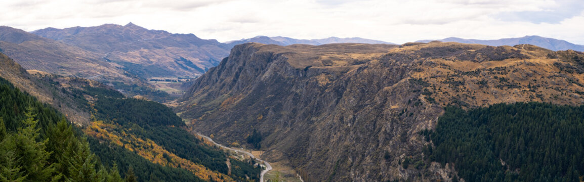 Panoramic scenery of New Zealand's natural landscape with mountains and Queenstown Hill, and Gorge Road winding between the valleys in the distance.
