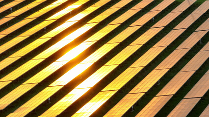 The blazing sun paints the sky in fiery hues as it sets over the solar plant, casting a breathtaking display of vibrant oranges and reds across the horizon. Clean energy and green technology concept.
