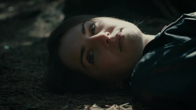 young female lying on the ground in a forest. 