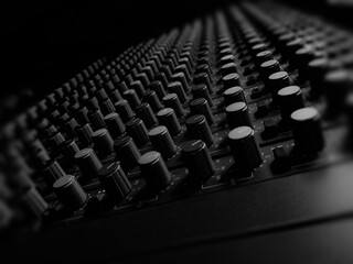 Analogue audio mixing desk,view from the side,in monochrome,showing individual channels,eq,volume...