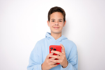 Portrait of boy using smartphone texting, standing isolated on white background.