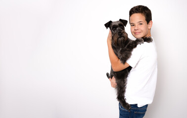 Happy young man holding black schnauzer dog in hands on white background in studio with copy space