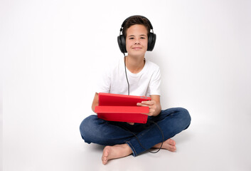 Portrait of caucasian child boy sitting on floor using tablet in casual outfit isolated over white background