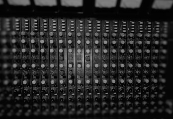 Analogue audio mixing desk,view from the above,in monochrome,showing individual channels,eq,volume knobs,vu meters