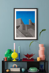Colorful composition on blue wall with mock up poster frame, black shelf, design accessories, and...