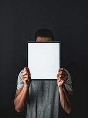 Naklejka premium Man holding a blank tablet in front of his face