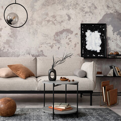 Loft style of modern apartment with grey design sofa, armchairs, ladder, black coffee table, black ladder, pedant lamp, carpet, decoration and elegant accessories . Concrete grunge wall. Template.