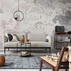 Loft style of modern apartment with grey design sofa, armchair, ladder, black coffee table, black ladder, pedant lamp, carpet, decoration and elegant accessories . Concrete grunge wall. Template.