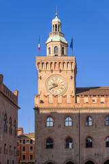 Fototapeta na wymiar Sunlight bathes the medieval clock tower of the Palazzo d'Accursio in Bologna, highlighting its architectural grandeur and timeless presence