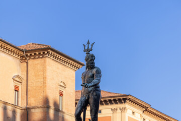 The imposing Neptune statue dominates the scene at Bologna Fountain of Neptune, crowned with a regal trident against a backdrop of clear blue sky and historic architecture